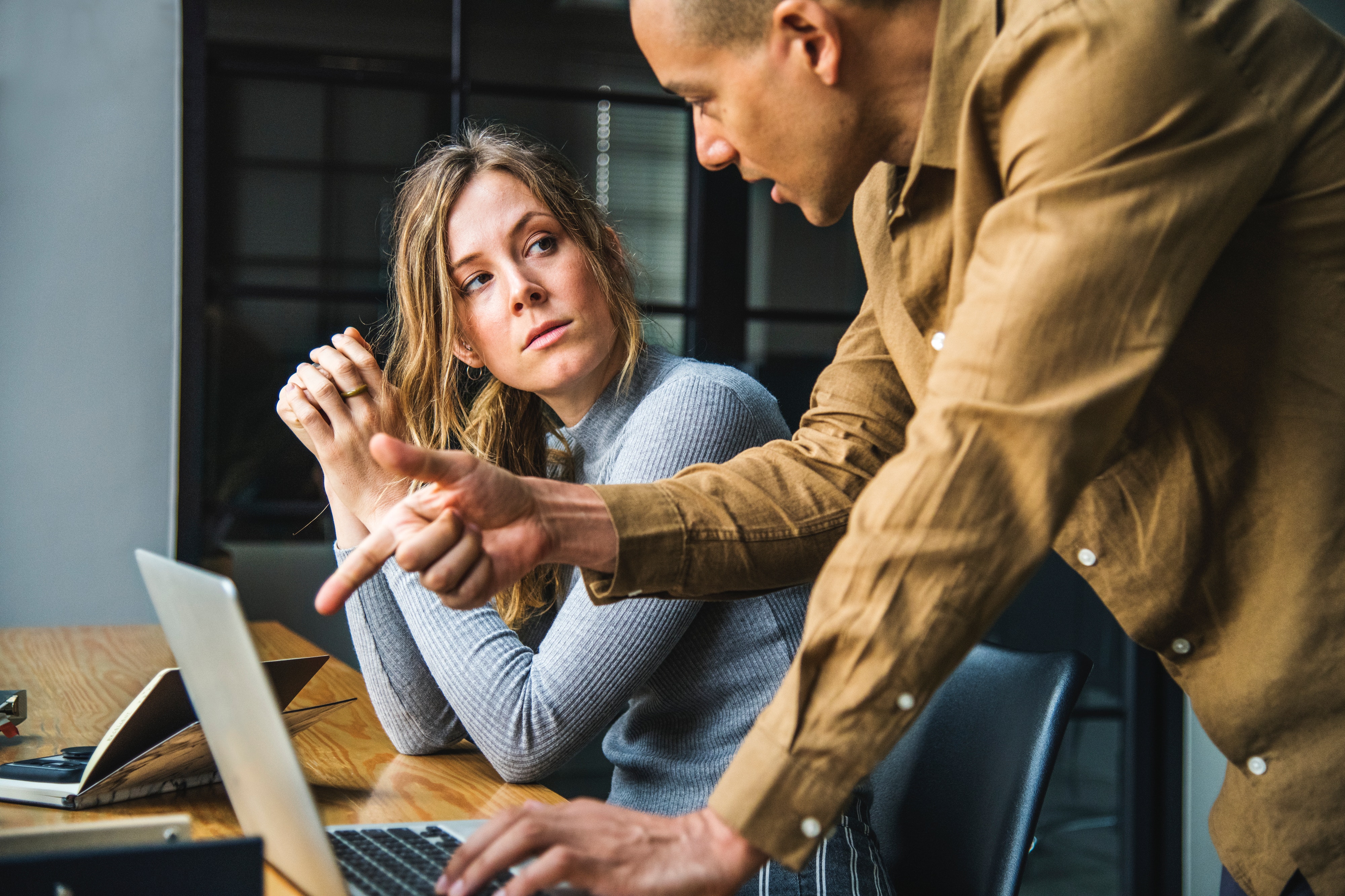 man showing woman how to do something at the laptop