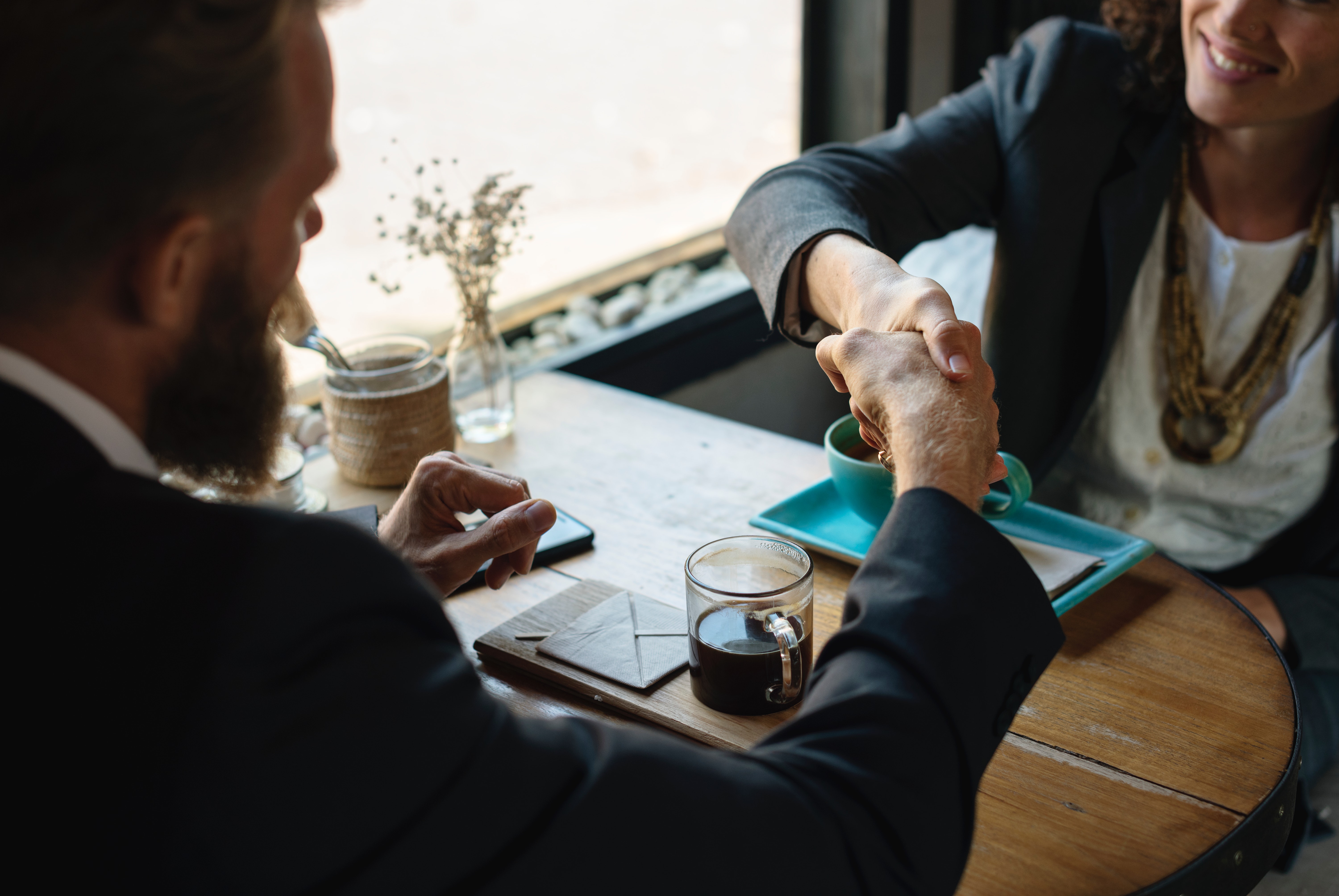 man and woman handshake over table